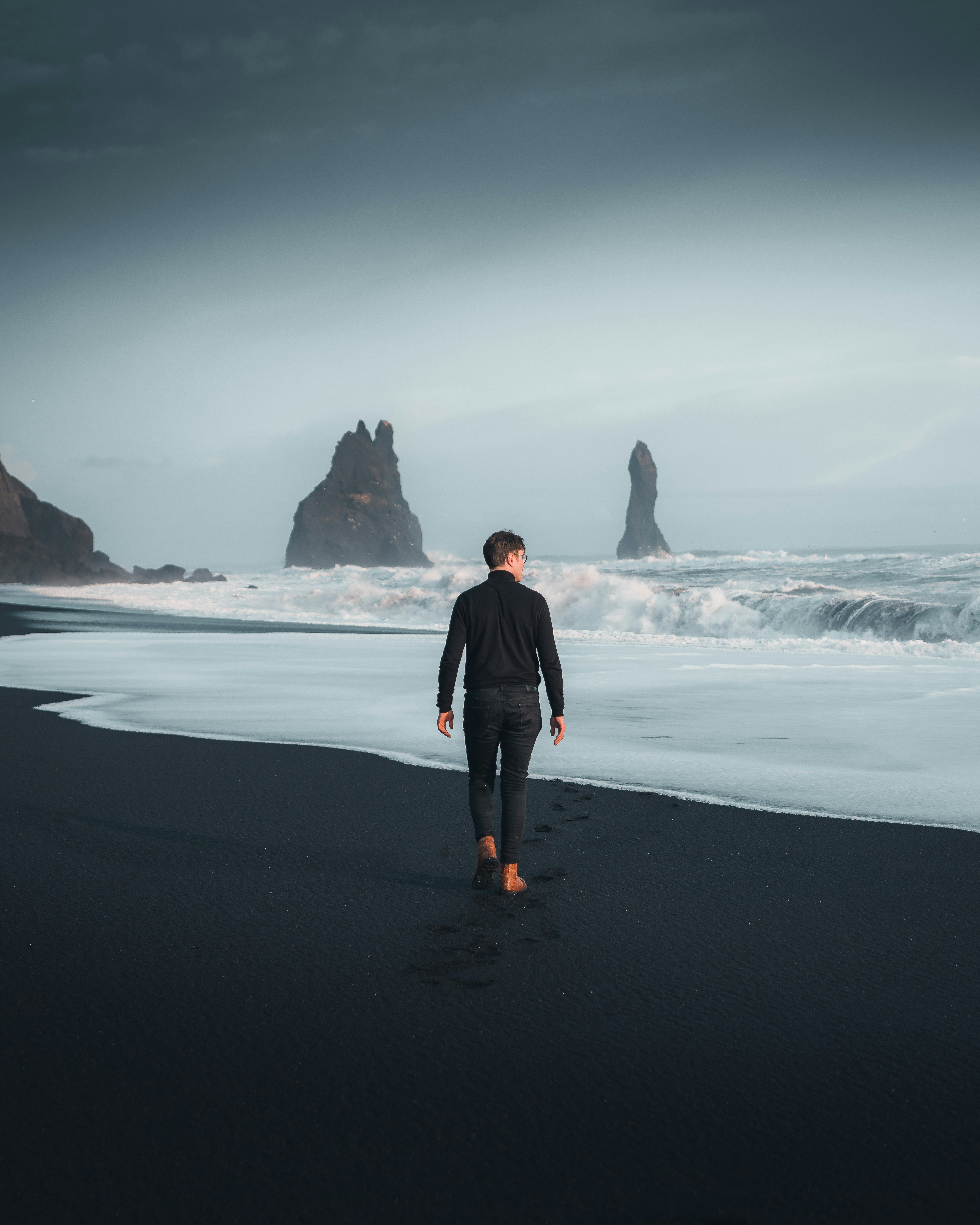 man in black jacket standing on seashore during daytime